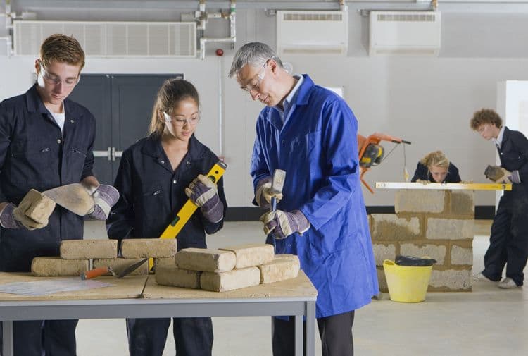 Auszubildende im Handwerk bei der praktischen Schulung mit Ausbilder Handwerksausbildung mit Auszubildenden und Ausbilder bei der Arbeit an einem Mauerprojekt – relevant für die Abrechnung von Auszubildenden in der Lohnbuchhaltung