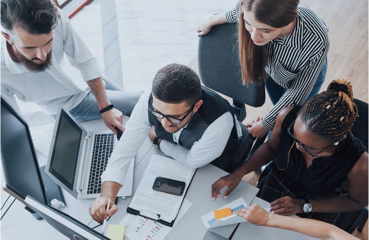 HR- und Payroll-Team analysiert digitale Lohnbuchhaltungsdaten Vier Personen im Büro analysieren gemeinsam digitale Lohn- und Gehaltsdaten am Monitor