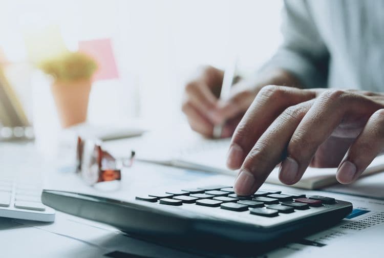 Gehaltsabrechnung präzise berechnen – Lohnbuchhaltung mit System Hand tippt auf Taschenrechner, im Hintergrund Notizen und Bürobedarf – Symbol für Lohn- und Gehaltsabrechnung