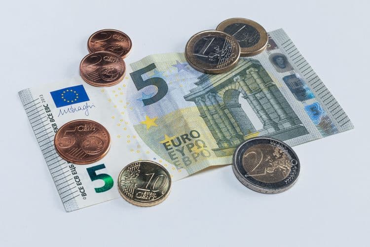 Löhne und Gehälter im Blick: Euro-Bargeld als Symbol für Entgeltabrechnung 5-Euro-Schein und mehrere Euro-Münzen auf weißem Hintergrund – Symbol für Lohn oder Vergütung