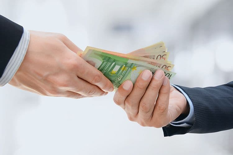 Geldübergabe zwischen zwei Personen in Anzügen Zwei Personen in Businesskleidung reichen sich Euro-Banknoten, darunter Scheine zu 50 und 100 Euro