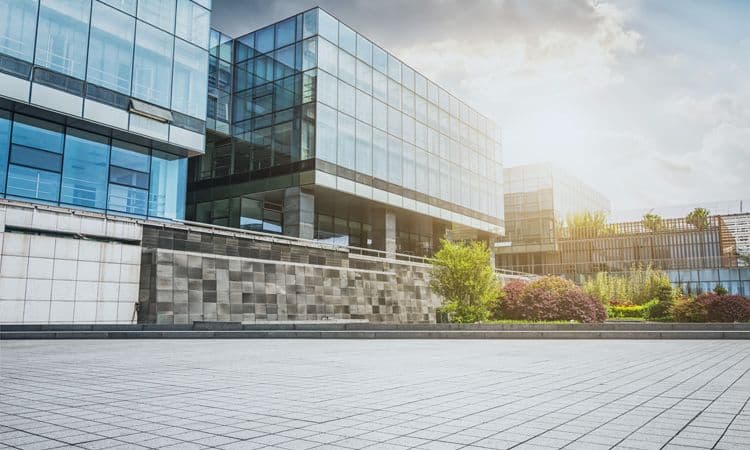 Modernes Bürogebäude mit Glasfassade bei Sonnenschein Großzügiger Vorplatz mit Blick auf ein modernes Verwaltungsgebäude mit Glasfassade und gepflegter Begrünung
