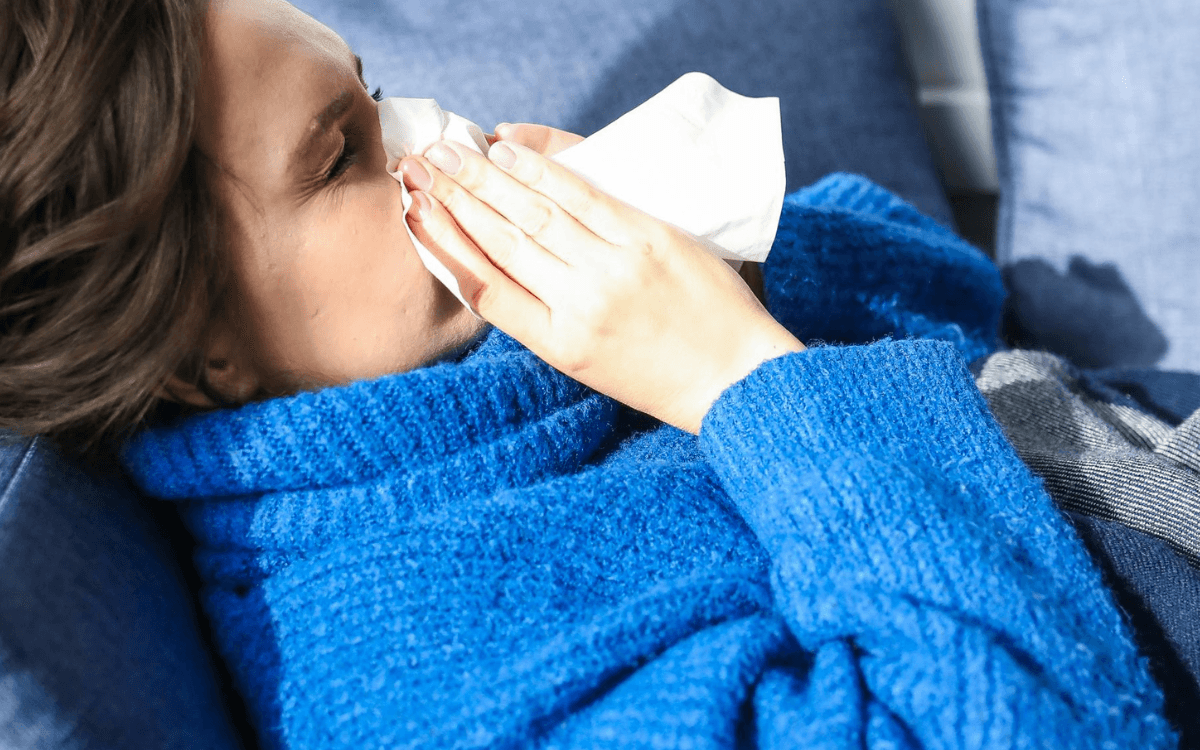 Eine Frau ist krank und hat Schnupfen - Lohnfortzahlung im Krankheitsfall
