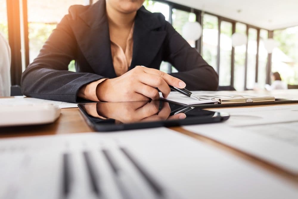 Professionelle Lohnbuchhaltung mit digitalen Tools und klarer Struktur Frau im Business-Outfit arbeitet mit Notizblock und Tablet an einem Schreibtisch – Symbol für digitale Lohnbuchhaltung