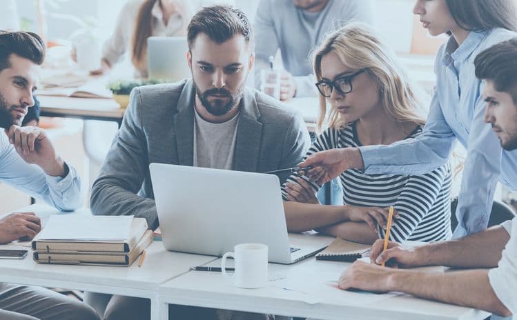 Team bei der gemeinsamen Abstimmung von Lohnabrechnungsprozessen in der Lohnbuchhaltung Mehrere Personen arbeiten gemeinsam an einem Laptop, analysieren Dokumente und diskutieren – sinnbildlich für Teamarbeit und Abstimmungen in der Lohnbuchhaltung