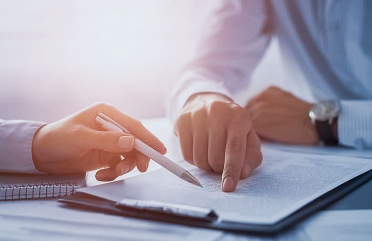 Lohnabrechnung im Dialog: Verträge und Abrechnungen richtig verstehen Zwei Personen besprechen gemeinsam ein Dokument und zeigen mit dem Stift auf Textstellen – symbolisch für Beratung zur Lohnabrechnung