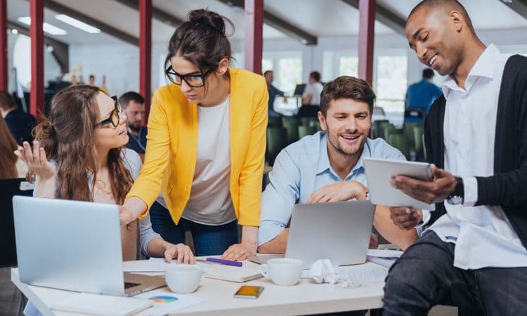 HR-Team bei der Planung digitaler Lohn- und Gehaltsabrechnungen Vier junge Menschen arbeiten im Büro an Laptops und Tablets an HR- und Lohnbuchhaltungsthemen