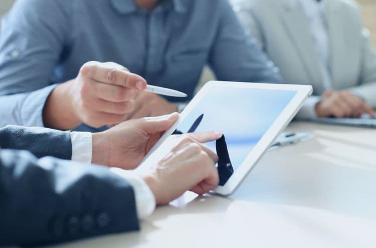 Digitale Payroll-Prozesse: Zusammenarbeit am Tablet in der Lohnbuchhaltung Zwei Personen zeigen auf ein Tablet bei der Arbeit an digitalen Lohnabrechnungsprozessen