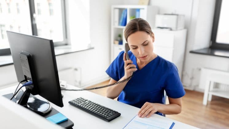 Lohnabrechnung im Gesundheitswesen – zuverlässig und digital verwaltet Medizinische Fachkraft im blauen Kittel bei der Büroarbeit am Schreibtisch – Lohnabrechnung in der Pflegebranche